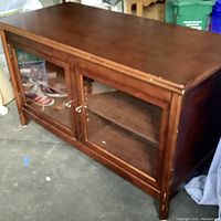 Front view of wooden entertainment console showing glass doors and wood construction