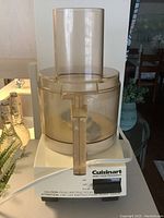 Side view of the Cuisinart food processor showing the base, control panel, and tinted transparent plastic work bowl with feed tube.