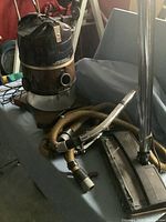 Photo of the Rainbow vacuum cleaner unit with hose, wand, and floor attachment arranged on a surface.