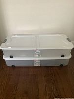 Two Sterilite under bed storage bins stacked together, lids closed, showing shape, lid design, and wheels.