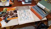 Overview photo showing antique paper dolls, Dennison craft books, letter storage box and book sleeves on a wooden table.