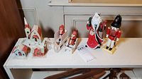 Photo showcasing overall lot arrangement with the three village buildings, two wood sleighs with figures, Santa figurine, and nutcracker