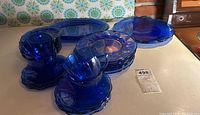 Wide view of the set showing teacups stacked with matching saucers, side plates, and large serving plates in cobalt blue glass.