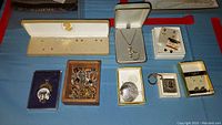Overview of the various costume jewelry pieces including necklaces, rings, earrings, and boxed items arranged on a blue surface.