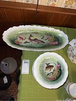 Oval serving platter with multiple hand-painted fish on green and white gradient background.