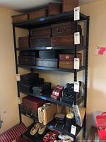Front view of both metal shelving units, showing four shelves with various wooden and metal boxes placed on shelves.