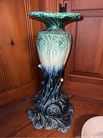 Full view of vintage ceramic pedestal showing ornate sculpted design and color gradient from dark blue base to green top.