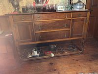 Full front view of cherry wood buffet with items on top and shelf below