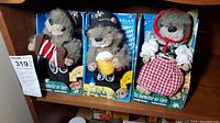Three Hias-Tirol animated musical gopher dolls in original blue packaging, each dressed in different traditional German/Alpine outfits, seen from the front.