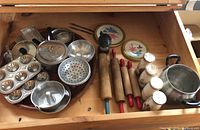 Top view of drawer with assorted vintage toy baking pans, rolling pins, and pots, salt and pepper shakers