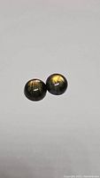 Pair of round cabochon labradorite stones showing golden multicolored flash on a white background.