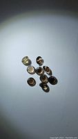 Group of 10 small round calibrated smokey quartz gemstones on white surface, showing sides and facets.