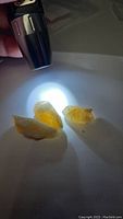 Three rough natural citrine crystals illuminated and displayed under a bright light, showing their translucent yellow-orange color and irregular rough shapes.