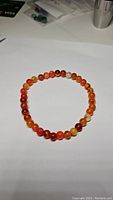 Photo showing natural red agate stretchy bracelet arranged in a circle on a white background.