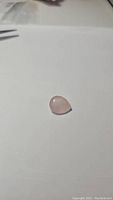 Clear photo of the pear cut rose quartz gemstone on a white background showing its light pink color and faceted surface.