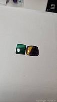 Two polished gemstones on white background: green malachite and purple fluorite.