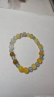 Bracelet laid out on white background showing alternating blue fluorite and yellow agate round beads.