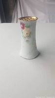 Front side view of the small antique vase showing hand painted pink and white flowers with green leaves and gold rim.