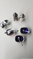 Top view showing two silver-plated salt cellars with cobalt blue liners and small spoons, two silver-plated napkin rings, and salt & pepper shakers.