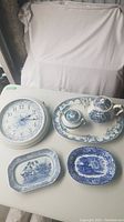 Overview of clock, teapot, sugar bowl, medium serving plate, and two small serving trays with blue and white design