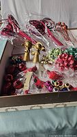 Photo of various Christmas baubles, bows, and two gold angel figurines arranged in a box.