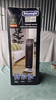 Box of DeLonghi ceramic tower heater showing product image and 1500 watts power rating.