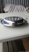 Closed view of silver plated serving dish with lid showing tarnish and handles on lid.