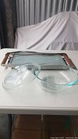 Glass casserole dish with matching clear glass lid shown next to warming tray.