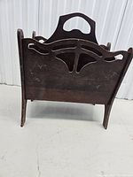 Side view showing decorative carved cutouts and handle on wood magazine rack.