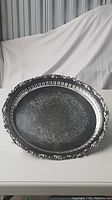Full view of large oval silver plated serving tray showing ornate edges and engraved surface.