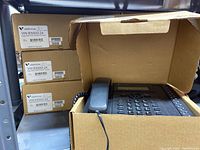 Four boxed Vertical Edge 5000 IP phones stacked, with one open box showing the phone inside.