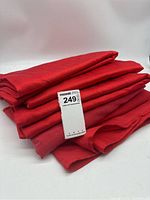 Stack of five red fabric table covers with a price tag showing $2.49 each approximately.