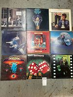 Front view of 9 LP record albums arranged in a 3x3 grid on floor, showing album cover art