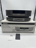 Front view of stacked main unit and CD module on original box with remote control and lot sticker visible