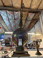 Full view of iridescent globe floor lamp showing large spherical glass shade and brass base with detailed design and claw feet.