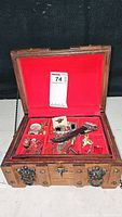 Open treasure chest jewelry box filled with men's jewelry, red velvet lining, top lid open showing contents