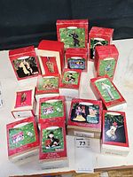 Multiple boxed Hallmark Keepsake ornaments arranged on table, showing red and green themed packaging with images of ornaments inside.