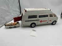 Front and side view of large white Tonka Rescue truck toy, with trailer and stretcher holding a figure. Shows overall condition and decals.