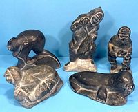 Group photo of all five Inuit stone carvings showing front views of human and animal figures against blue background.