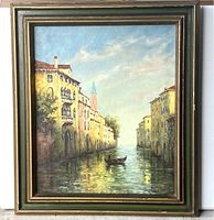 Framed oil painting depicting a Venetian canal scene with buildings and gondolier, signed by artist.