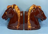 Pair of ceramic horse head bookends with brown and yellow glaze shown from side view.