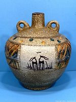 Front view of vintage pottery vase showing stylized animal painting and speckled glaze.