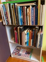 Three shelves filled with an assortment of hardcover and paperback books covering topics such as art, poetry, fiction, and nonfiction.