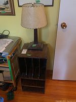 Full view of wood lamp with fabric shade on top of plywood LP record cabinet showing lamp base and cabinet storage slots.