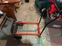 Photo of the four wheel dolly showing side view with handle and wheels on concrete floor with other household items.
