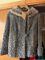 Front view of Persian wool fur coat with light mink fur collar, medium-large size, hanging on wooden hanger.