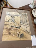 Full view of framed watercolour painting showing rural scene with wooden farming equipment and barn wall.
