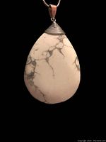 Close-up of the white turquoise teardrop pendant showing its grey veining and silver cap with ridged design detail.