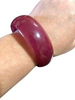 Bakelite bangle worn on wrist showing polished glossy finish and deep red color