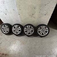 Four wheel-and-tire assemblies lined against concrete wall